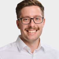 Porträtfoto von Christopher Egly, Brustaufnahme vor neutralem, hellem Hintergrund. Er trägt ein weißes Hemd und blickt freundlich in die Kamera.